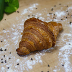 Butter croissant sitting on baker's bench with flour