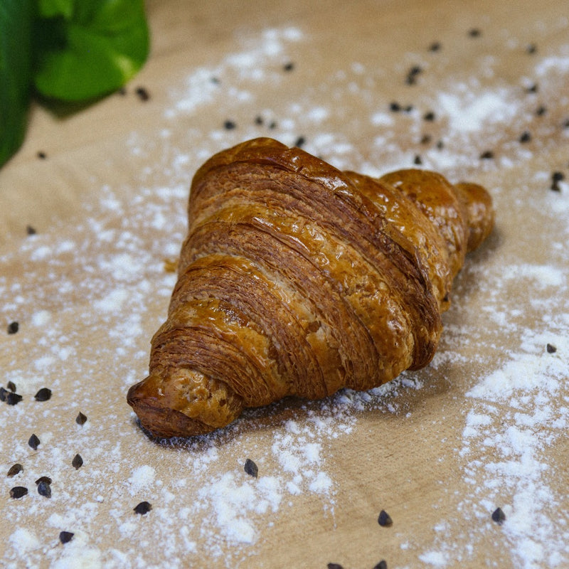 Butter croissant sitting on baker's bench with flour