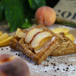Palisade peach puff on a bakers bench with flour and sliced peaches.