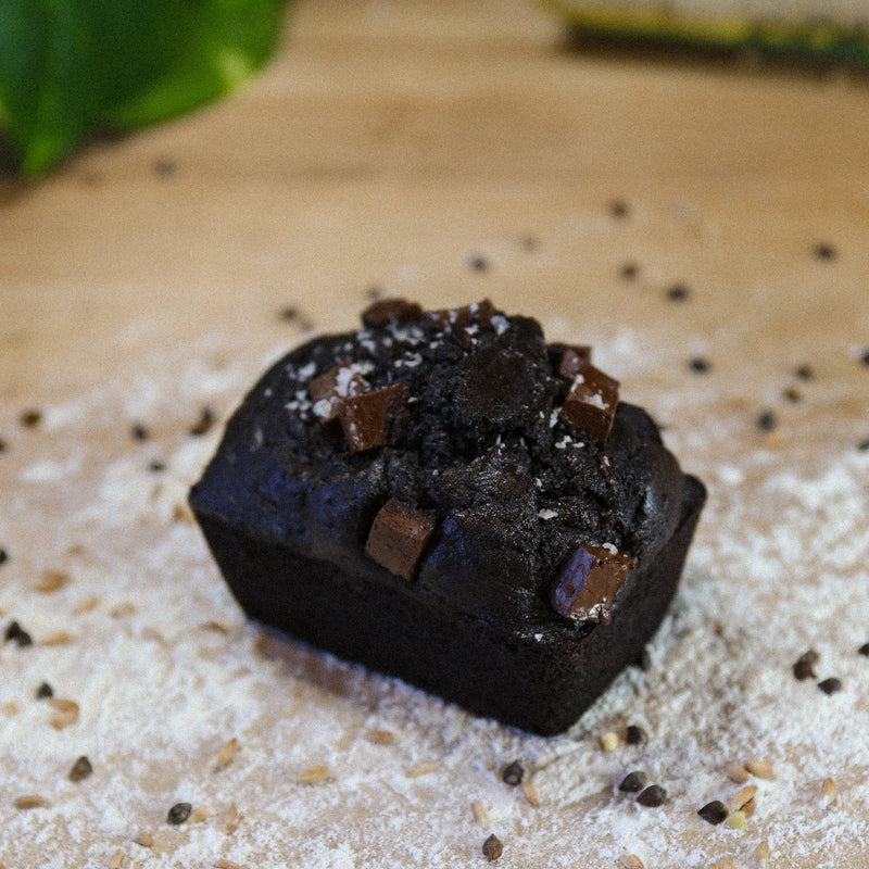 Noir Chocolate Zucchini Cake on a baker's bench with flour.